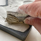 A close up images of a hand using a metal ruler and scraping excess clay from Iron Orchid Designs Persephone mould