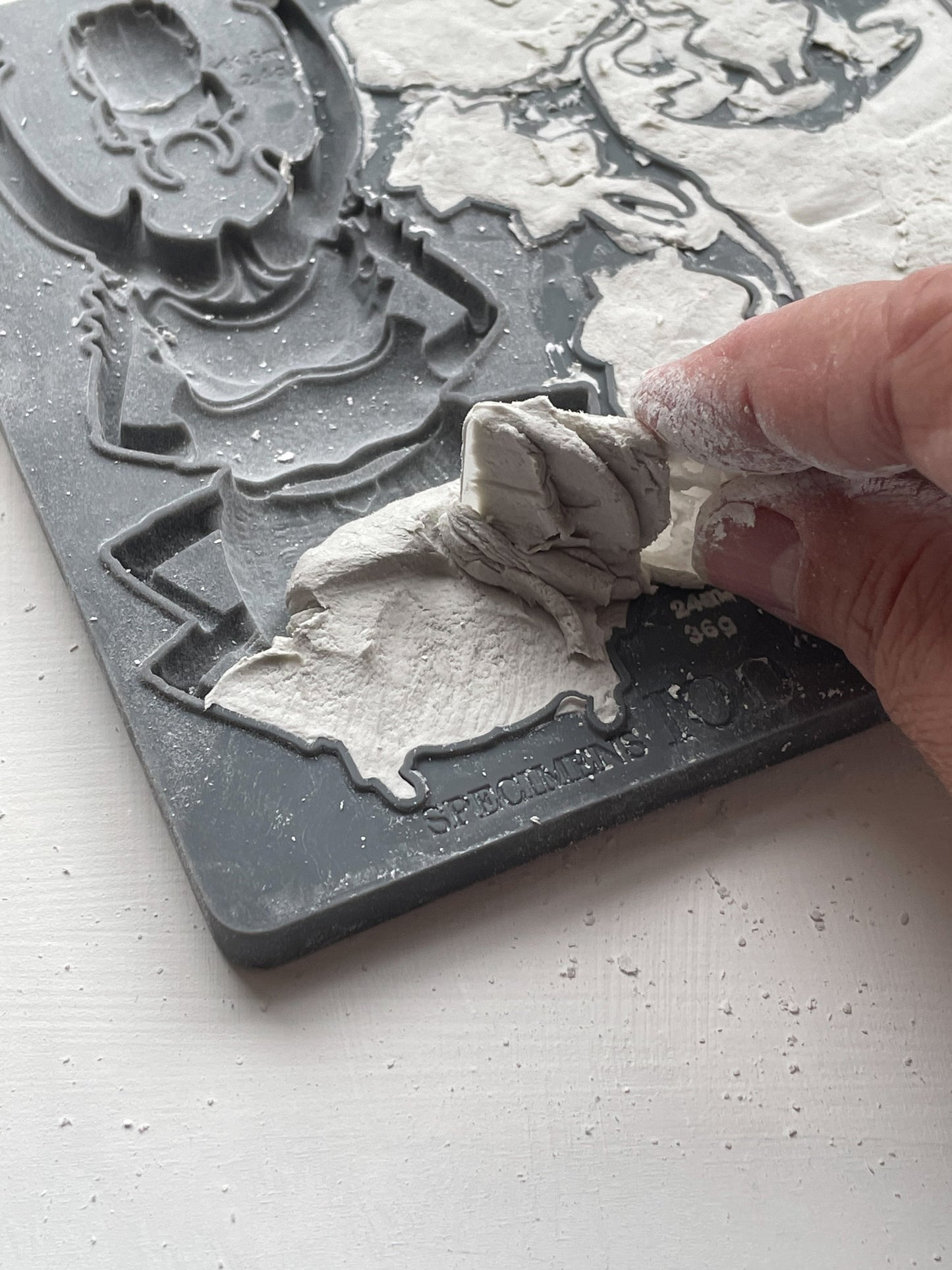 A close up image of a hand removing excess clay from Iron Orchid Designs Specimens mould