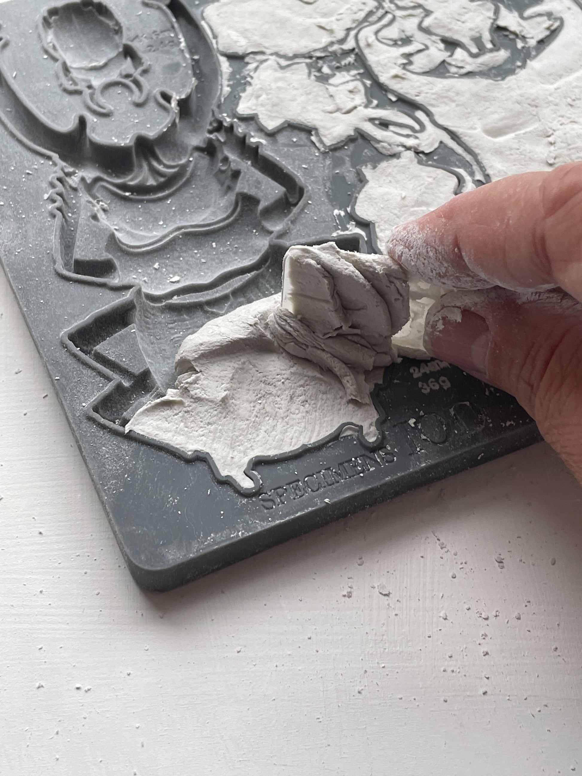 A close up image of a hand removing excess clay from Iron Orchid Designs Specimens mould