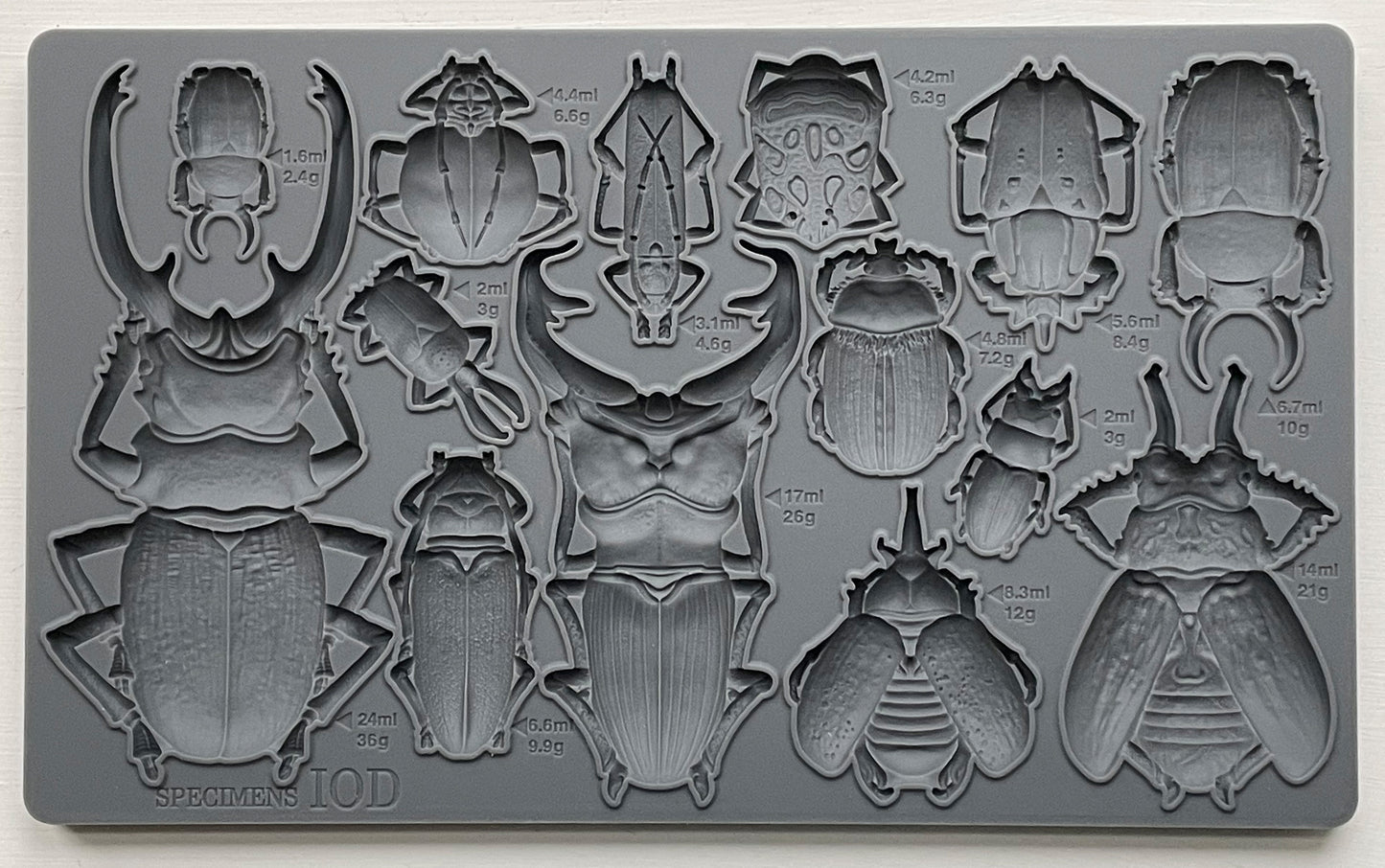 A grey silicone mould from Iron Orchid Designs featuring various insect shapes, such as beetles and bugs for crafting and baking purposes.