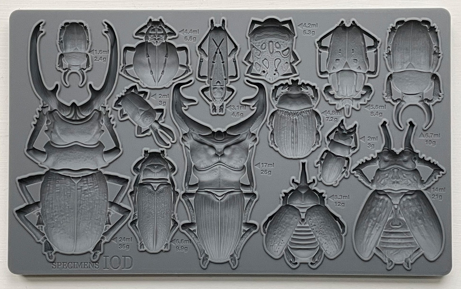 A grey silicone mould from Iron Orchid Designs featuring various insect shapes, such as beetles and bugs for crafting and baking purposes.