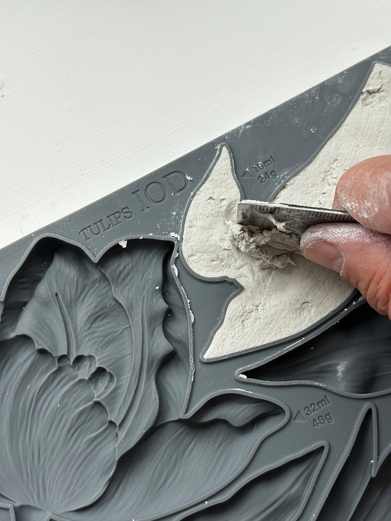 Close-up of a hand using a tool to shape air dry clay in the Iron Orchid Designs Tulips mould