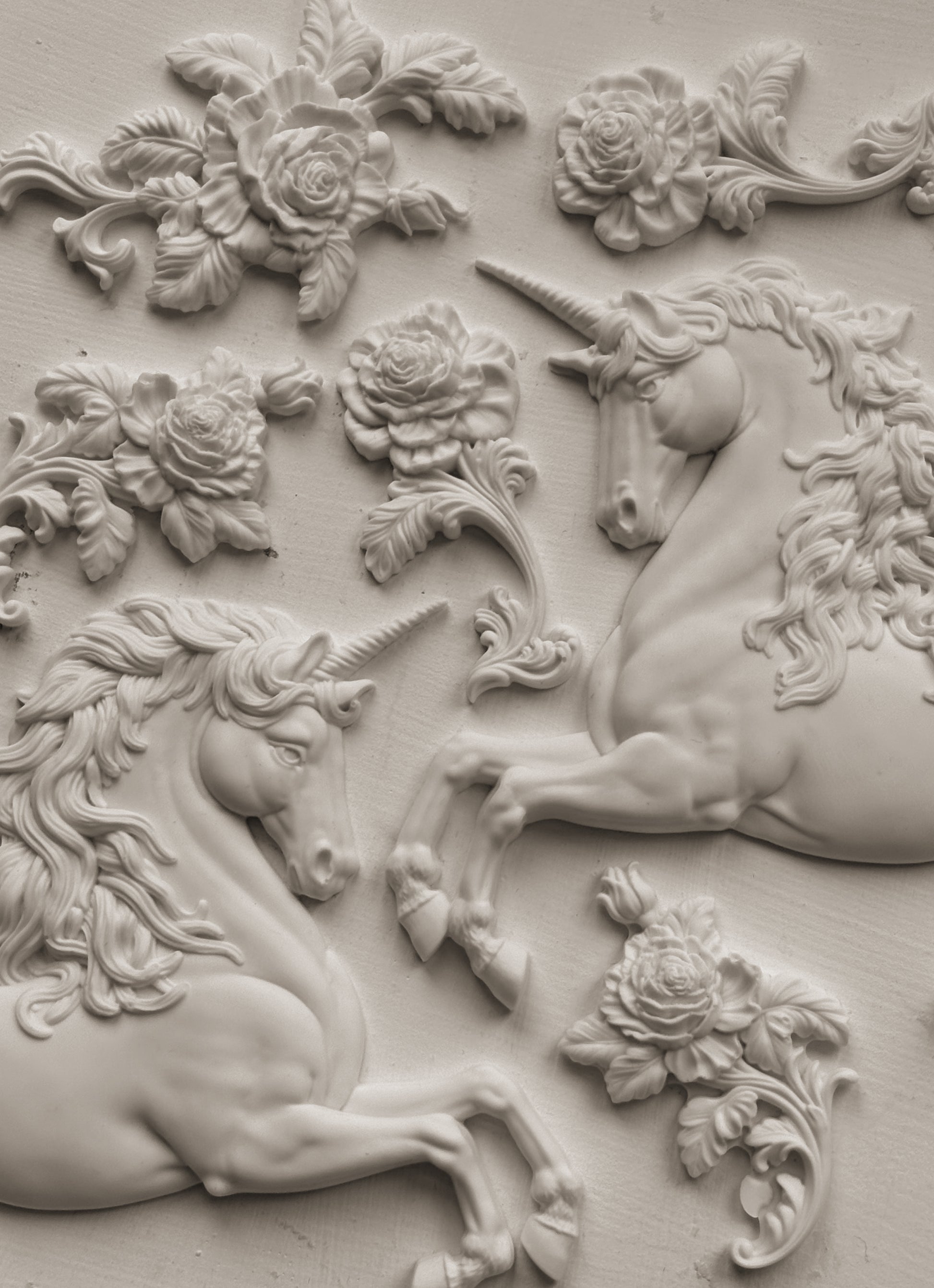 White clay castings of Iron Orchid Designs Unicorns and flowers on a white background