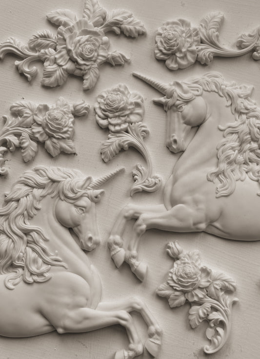 White clay castings of Iron Orchid Designs Unicorns and flowers on a white background