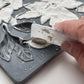 A close up image of a hand removing excess clay from iron Orchid Designs Viridis mould