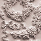 A close up photograph of decorative white floral and leaf castings on a white background from Wreaths and Swags, iron Orchid Designs