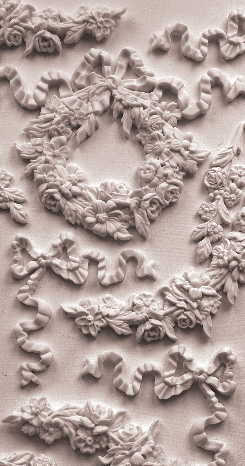 A close up photograph of decorative white floral and leaf castings on a white background from Wreaths and Swags, iron Orchid Designs