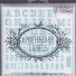A photograph of the front of the box for Iron Orchid Designs Apothecary Labels Stamp. The image shows the name of the stamps and some of the letters of the alphabet stamps can be seen in the background