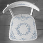 A wooden chair painted white and stamped with Iron Orchid Designs Brambles and Berries stamp. The chair is stamped with blue ink and is standing on a pale coloured planked floor