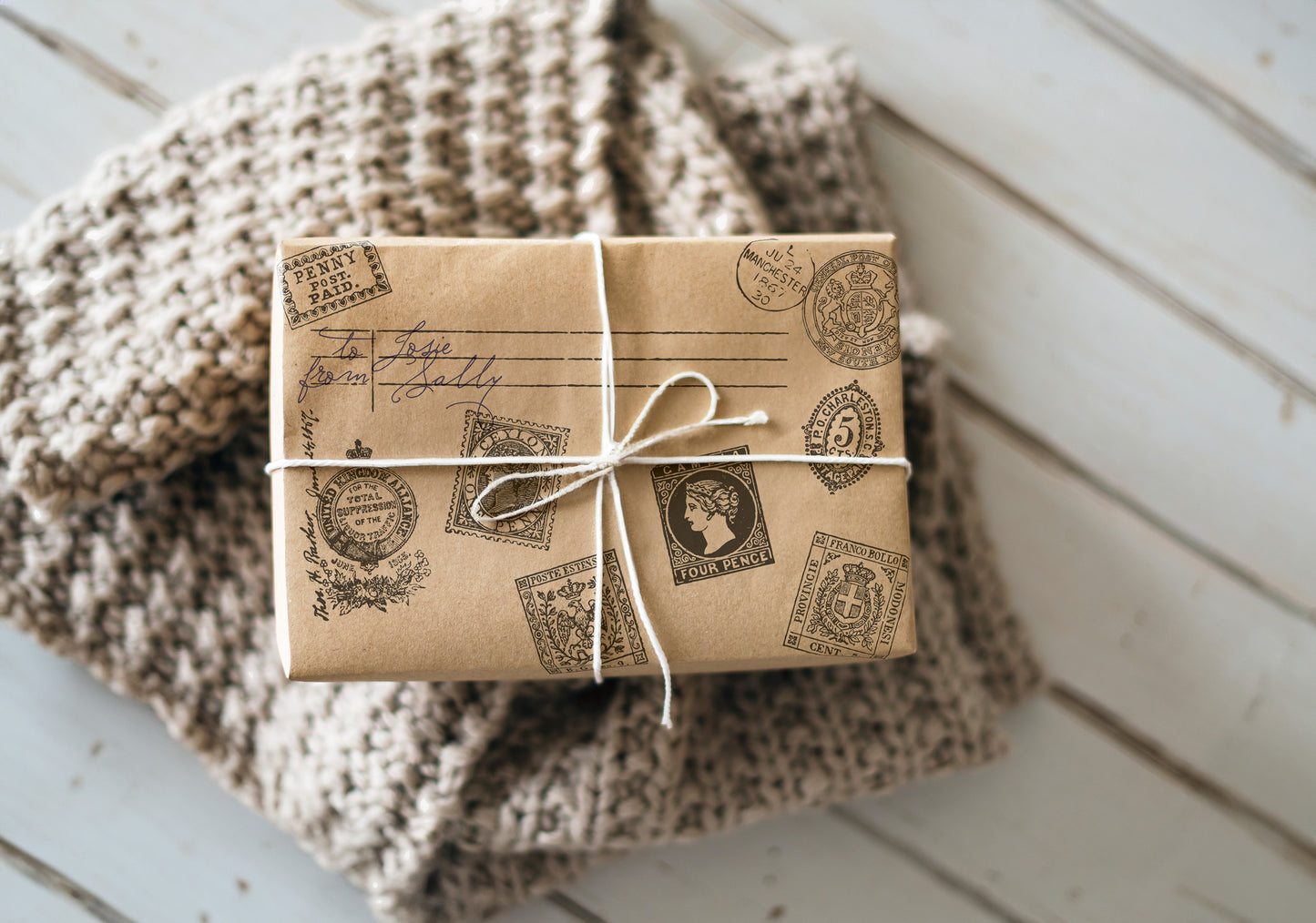A prersent wrapped in brown paper which has been stamped with Ephemeral Type Stamp from Iron Orchid Designs. The parcel is tied with white string and is standing on a woollen blanket