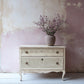 Vintage-style chest of drawers stamped with Iron Orchid Designs Lace Stamp with a vase of flowers against a textured wall.