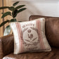 A striped cushion that has been stamped with a grain sack effect using stamps from Iron Orchid Designs Mercantile stamp. The cushion has been placed on a tan leather chair and is next to a large leaved plant.