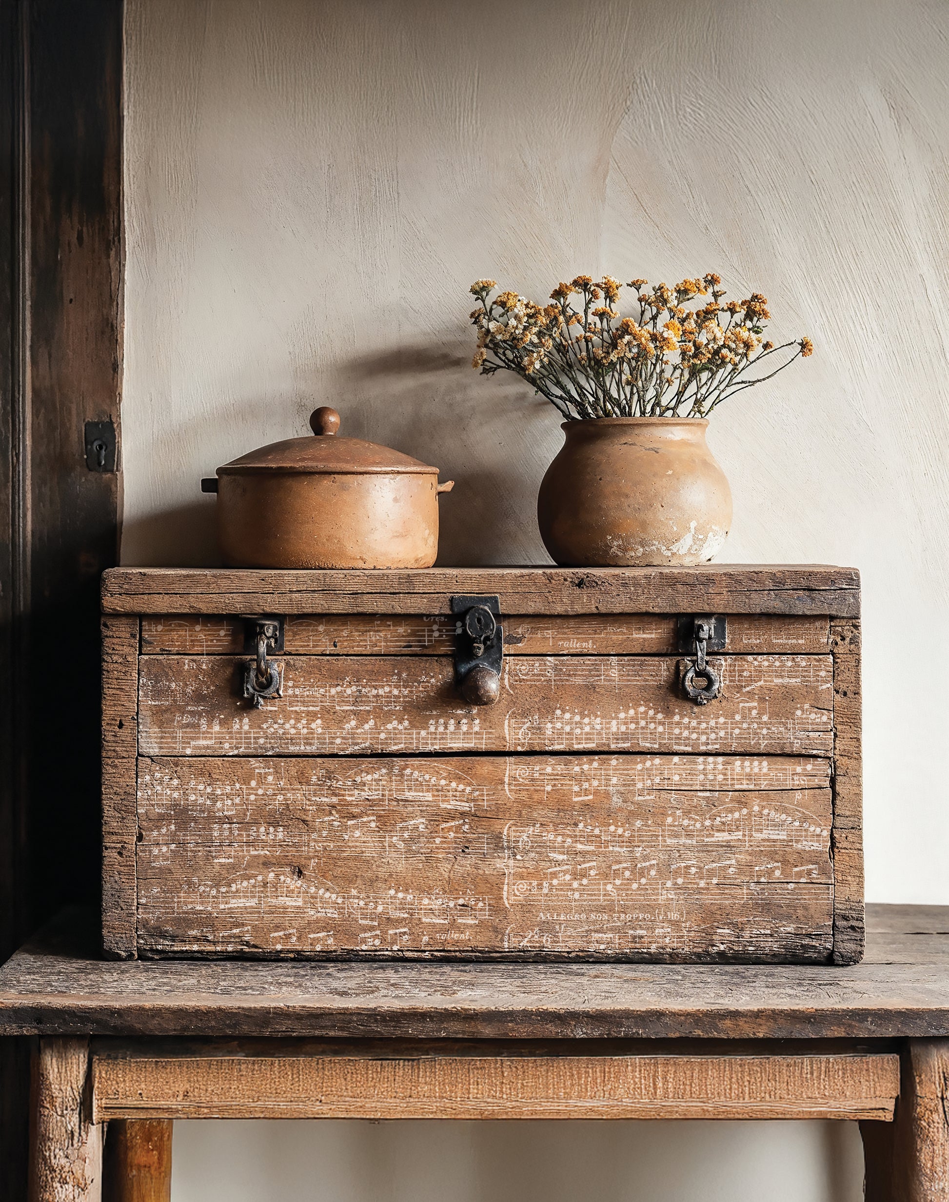Vintage stamped wooden box with ceramic pot and vase on a rustic surface