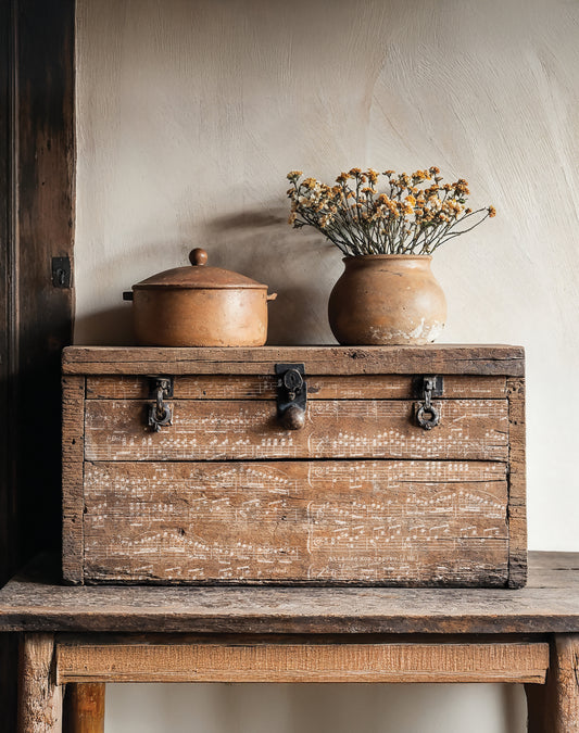 Vintage stamped wooden box with ceramic pot and vase on a rustic surface