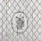 A vintage picture created using Iron Orchid Designs Veranda stamp. There is a flower filled oval frame surrounded by latticework. The image is printed using grey ink on a planked background