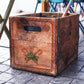 An image showing a wooden box that has been stamped with Iron Orchid Designs Frosty's Sweet Shoppe stamp. The box is standing on a tiled floor next to a table.