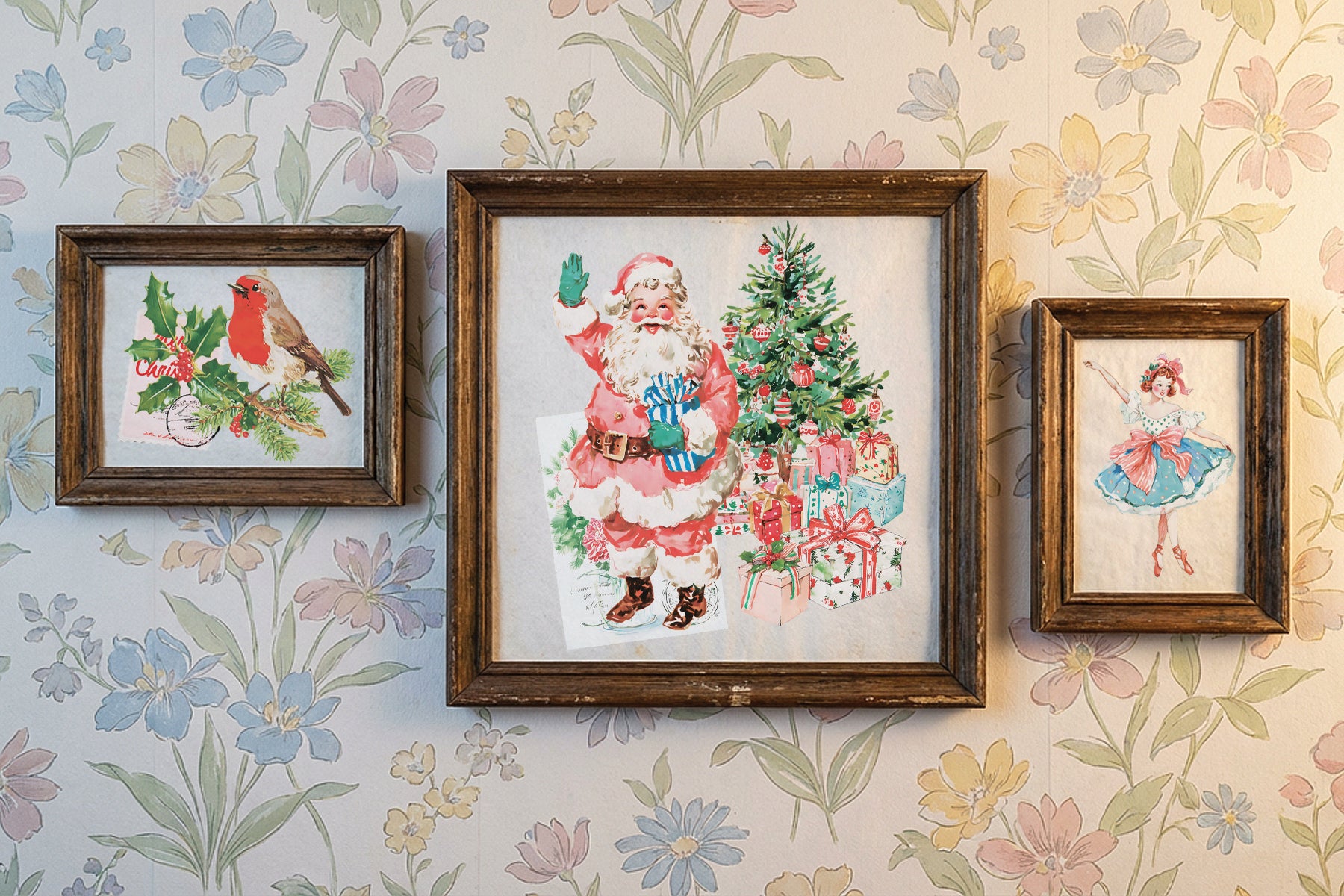 Three framed vintage-style artworks hanging on a floral wallpaper background. The center, largest framed piece shows Santa Claus beside a Christmas tree and presents; the left smaller frame shows a bird with holly and roses; the right smaller frame shows a ballerina. From Iron Orchid Designs.