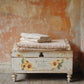 Vintage chest with floral decal and towels against a textured wall from Iron Orchid Designs Flowers By The Poets transfer