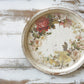 Round decorative tray with floral design on a wooden surface from Iron Orchid Designs Flowers By The Poets transfer