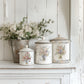 Decorative white pots with floral designs on a white surface with a wooden background