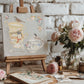 Artistic setup with teacups  from Iron Orchid Designs The Belgravia transfer on canvas on an easel, surrounded by flowers and paint brushes