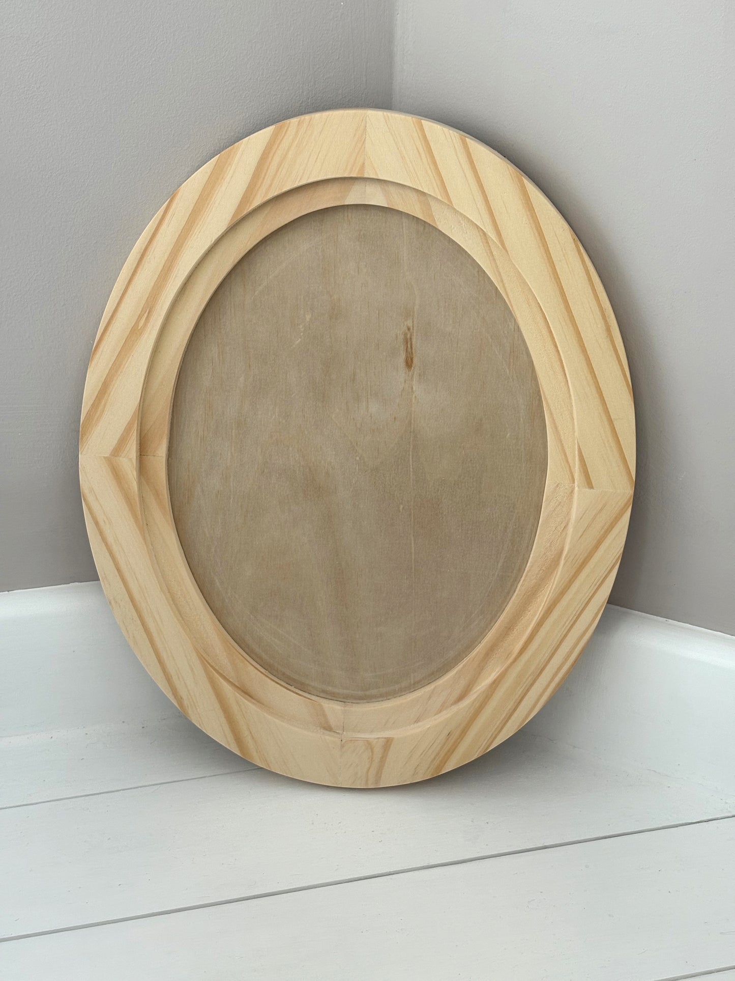 Wooden oval craft blank on a white surface with a grey background by Iron Orchid Designs