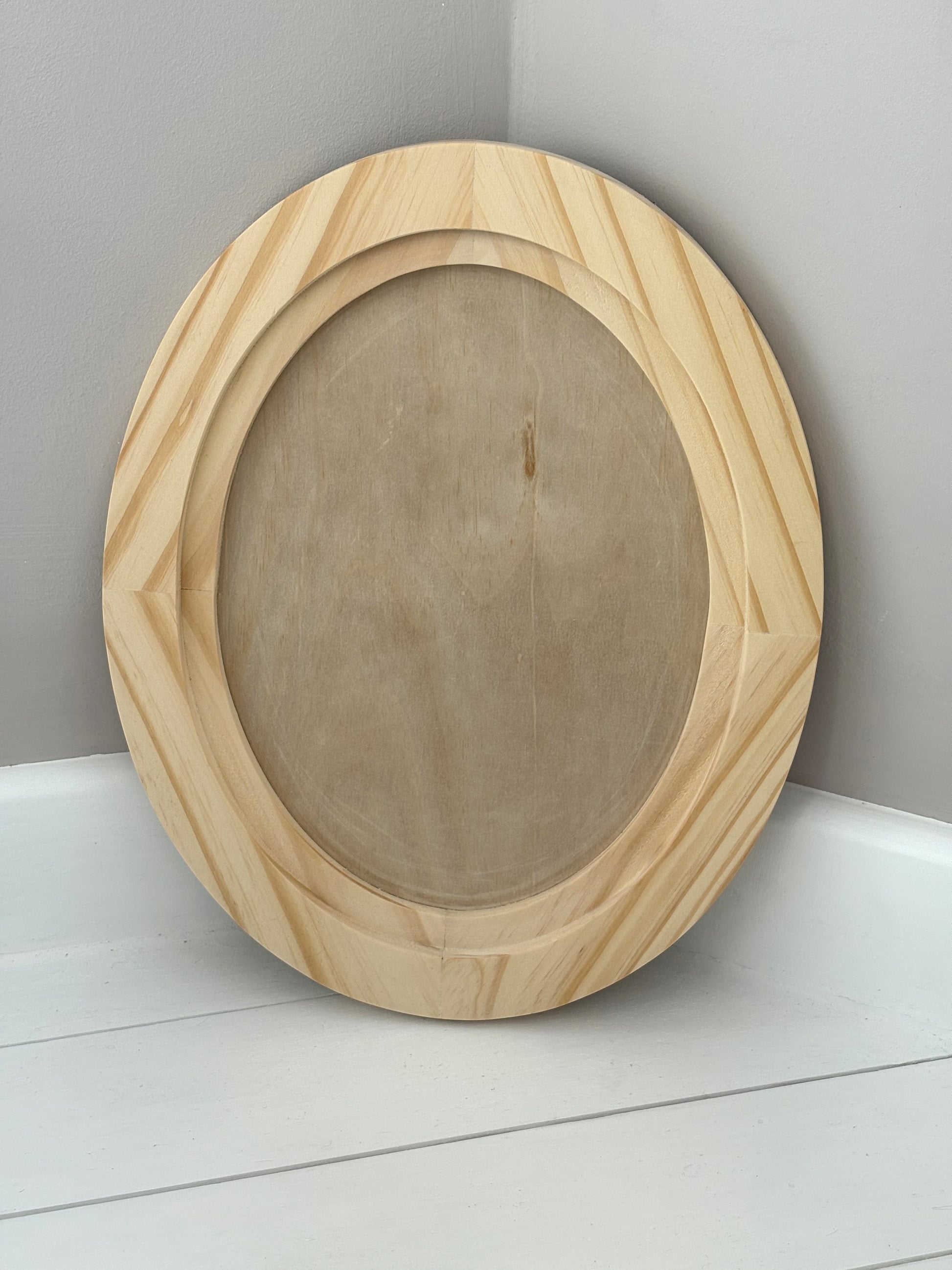 Wooden oval craft blank on a white surface with a grey background by Iron Orchid Designs