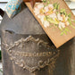 Decorative rusty milk churn with floral tag and star detail