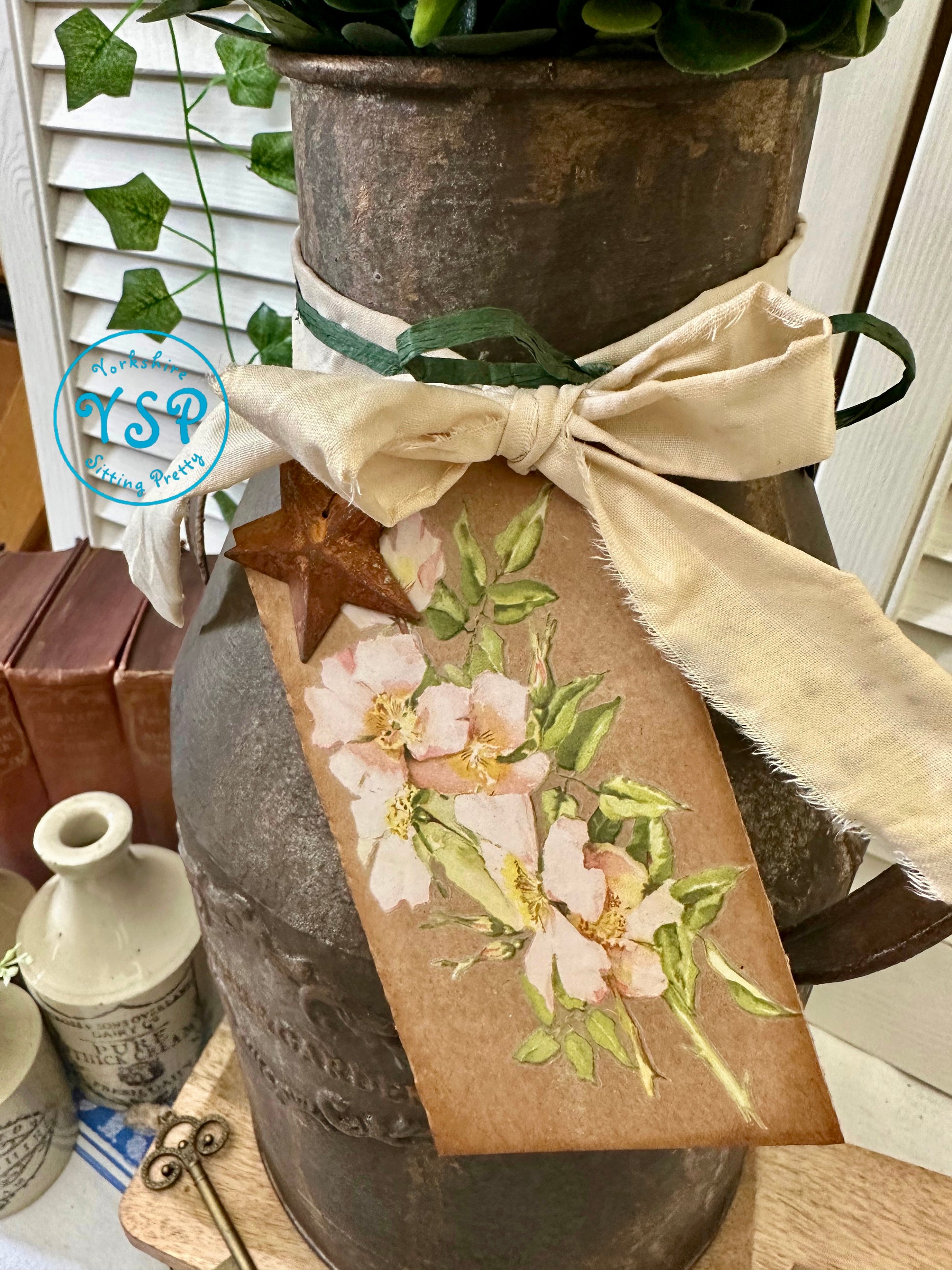 Decorative rusty milk churn with floral design tag 