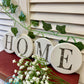 Four white round coasters painted white spelling out home set against a white background on a red surface