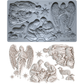 A I0D silicone mold set featuring detailed Christmas nativity and angel designs, shown both in its gray silicone form and as the finished light beige carved plastic pieces. Silent Night mould from Iron Orchid Designs.