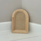 Wooden arch-shaped crafting blank on a white surface with a grey wall by Iron Orchid Designs 