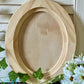Wooden oval craft blank on a surface with greenery and flowers by Iron Orchid Designs