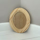 Small oval wooden craft blank on a white surface with a grey background by Iron Orchid Designs