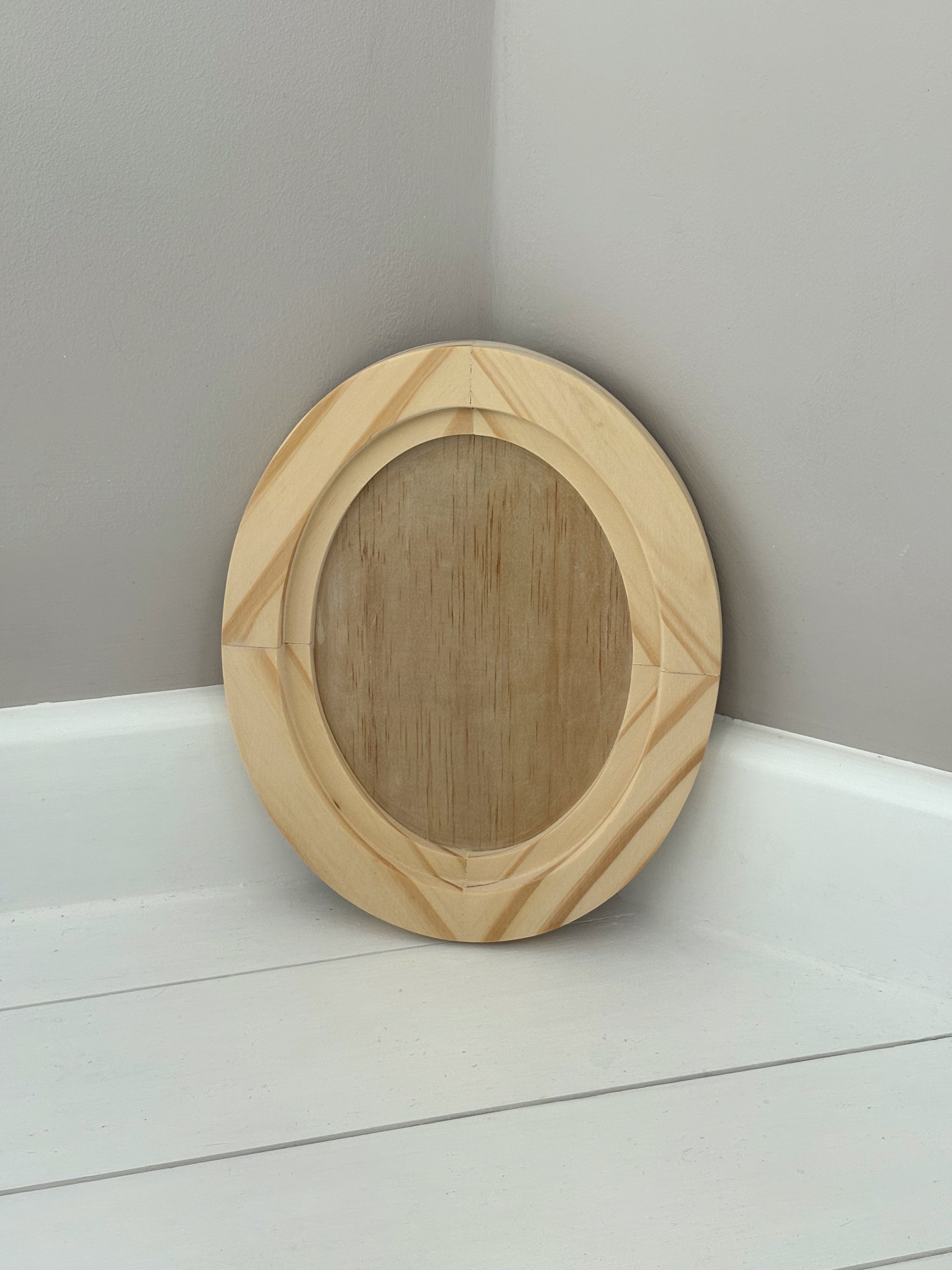 Small oval wooden craft blank on a white surface with a grey background by Iron Orchid Designs