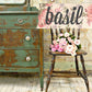 Vintage green dresser with a wooden chair holding pink flowers, against a floral background with 'basil' text.