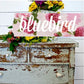 Vintage wooden chest with floral arrangement and 'bluebird' sign on a white wooden background