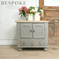 Gray cabinet with wooden top and floral arrangements on a wooden floor.