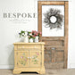 Vintage-style cabinet with floral design in a room with a wooden door and wreath.