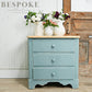 Blue dresser with wooden top against a rustic wooden wall