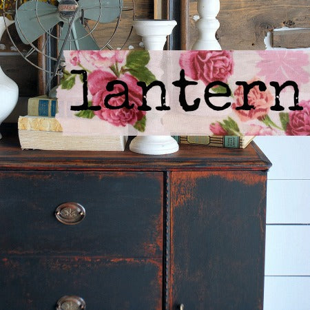 Decorative lantern with floral design and 'Lantern' text on a wooden surface.
