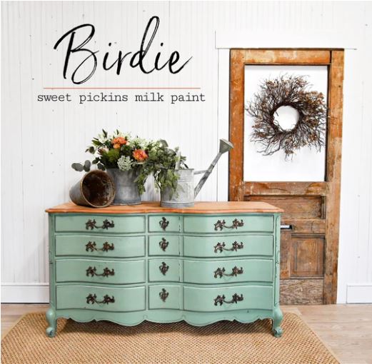 Green chest of drawers with a wooden top standing next to a wooden door.