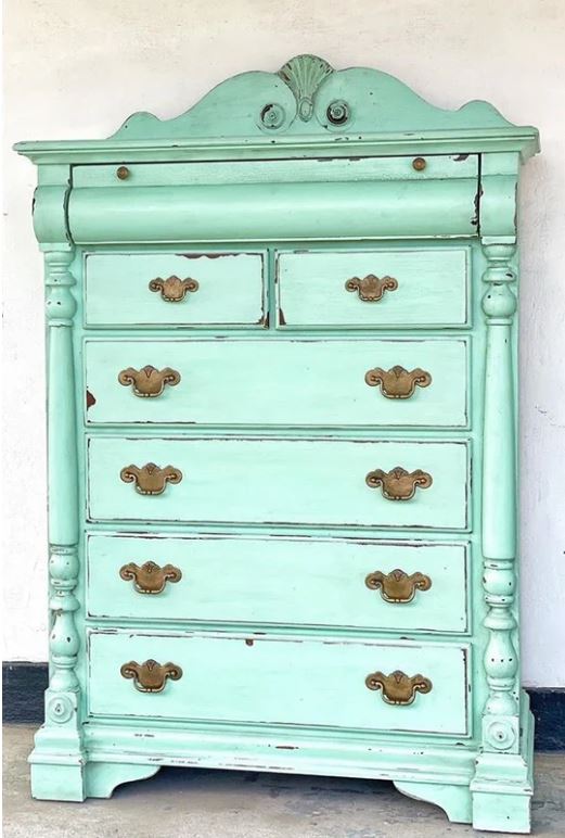 Mint coloured chest of drawers standing against a white wall