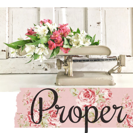 Vintage-style scale with flowers on a white wooden background, featuring the brand 'Proper'.
