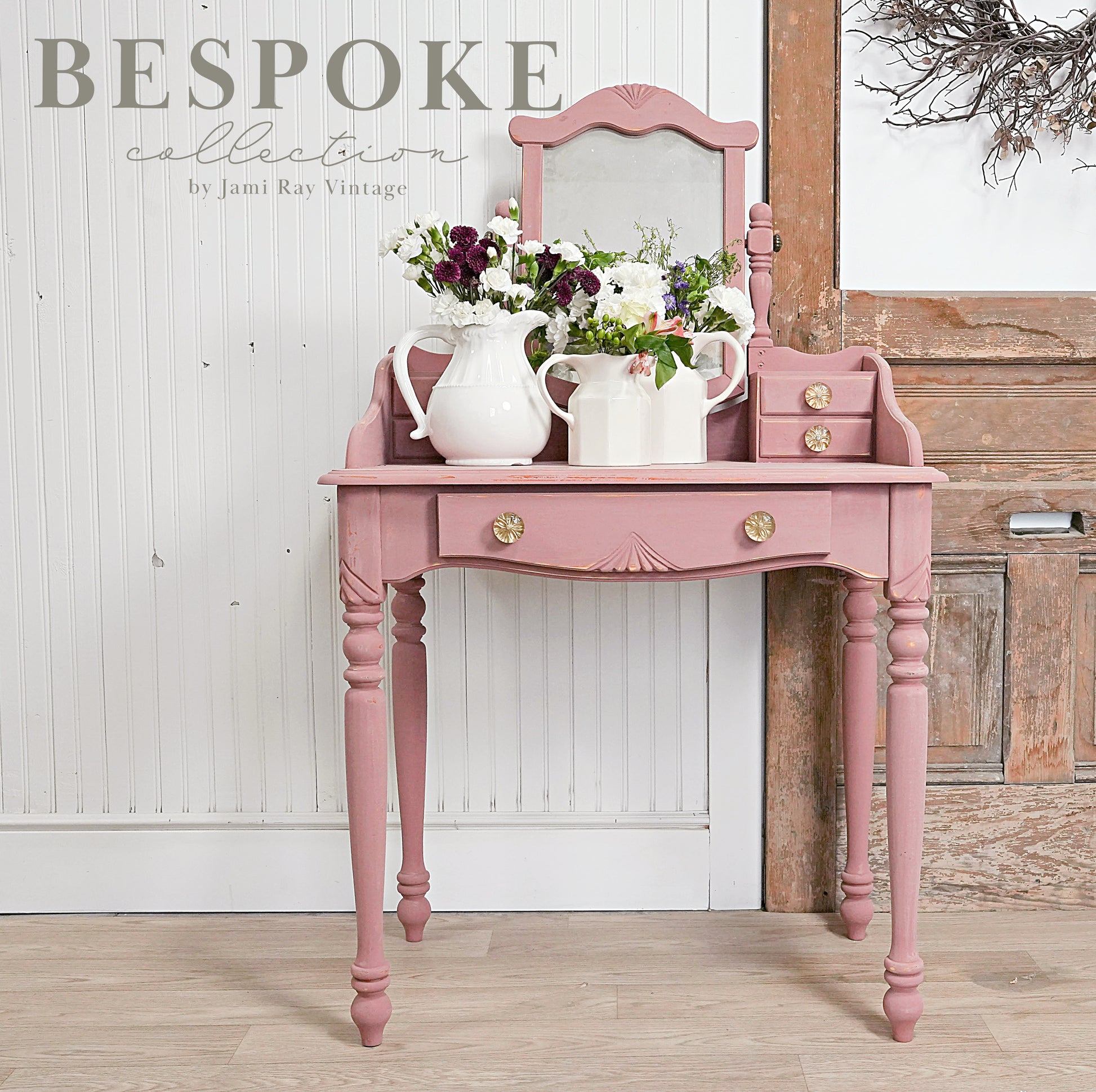 Pink vanity table with flowers and decor against a wooden wall, featuring 'Bespoke Collection' text.