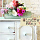 Floral arrangement in a green container on a white cabinet with 'Window Pane' sign.