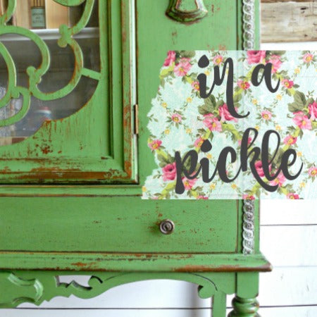 Green distressed cabinet with a decorative sign reading 'in a pickle' on a white background