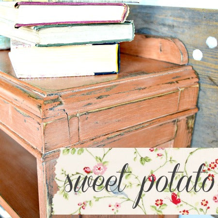 Vintage wooden desk with books on top, featuring a 'sweet potato' label with floral design.