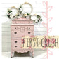 Pink vintage-style dresser with floral decorations against a white wooden background, featuring First Crush milk paint