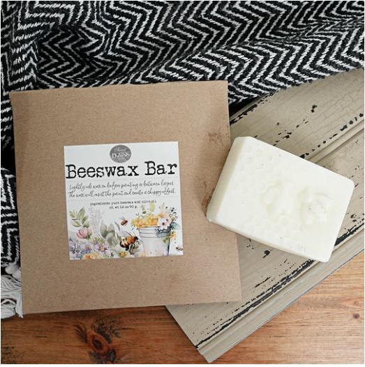 Sweet Pickins Beeswax bar on a wooden surface with a black and white patterned fabric in the background